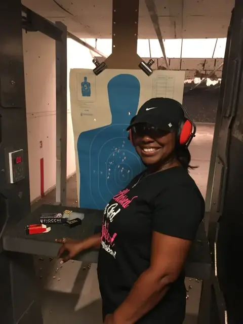 Trouble Defense student wearing eye and hearing protection beside her range target