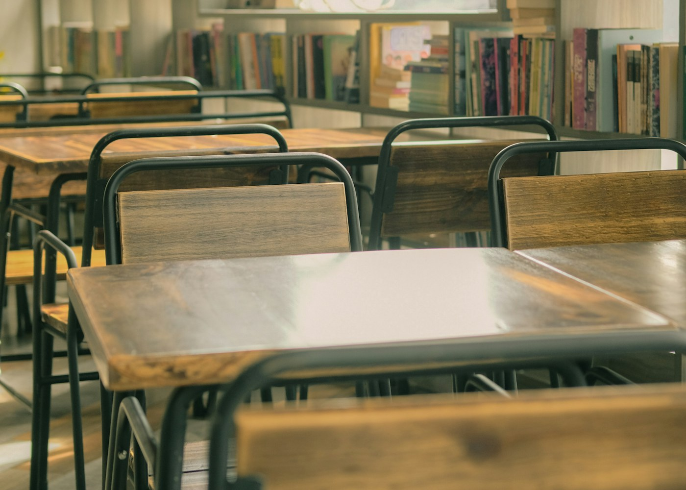 Empty study tables and chairs surrounded by library bookshelves